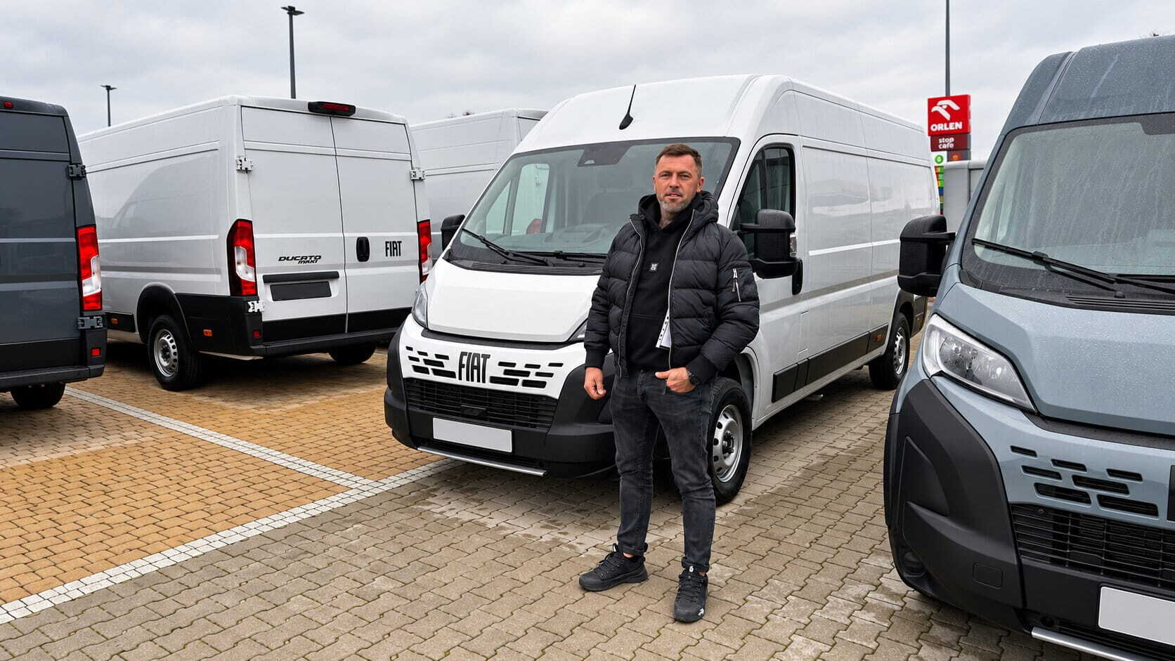 Mężczyzna wśród vanów Fiata na placu dealerskim